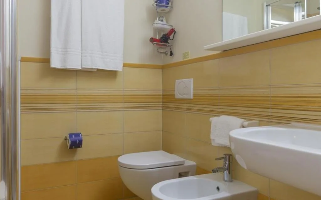 Bagno con piastrelle gialle, WC, bidet e lavabo bianco