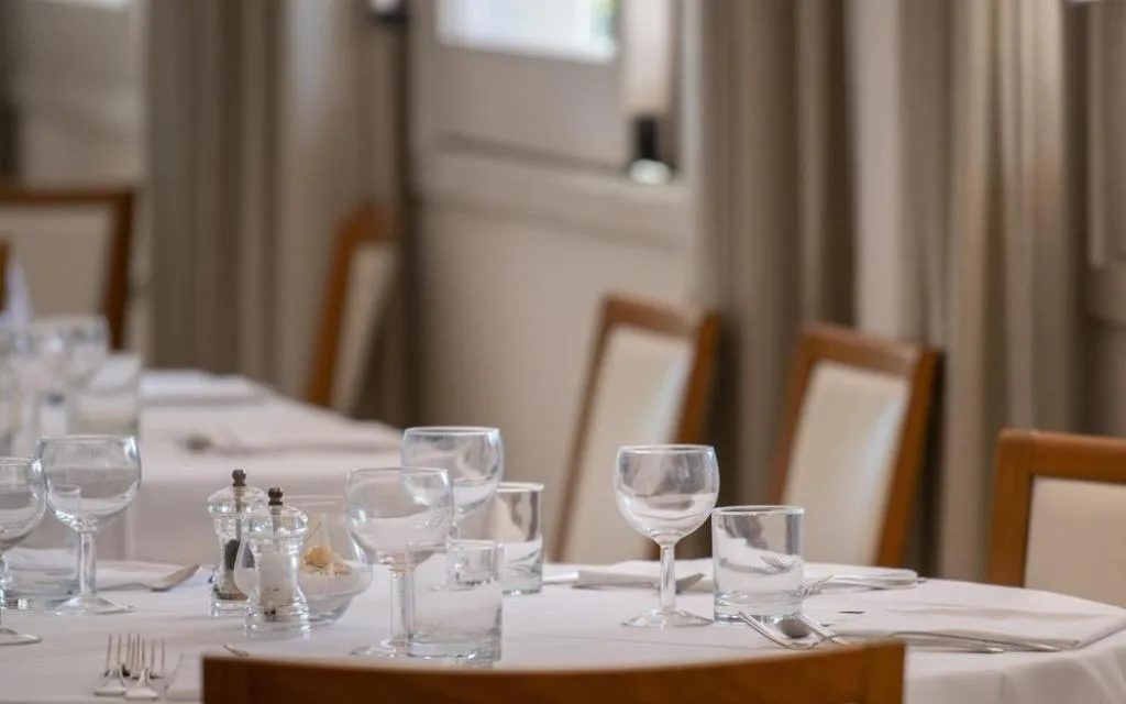 Tavolo del ristorante apparecchiato con bicchieri di cristallo e tovaglia bianca